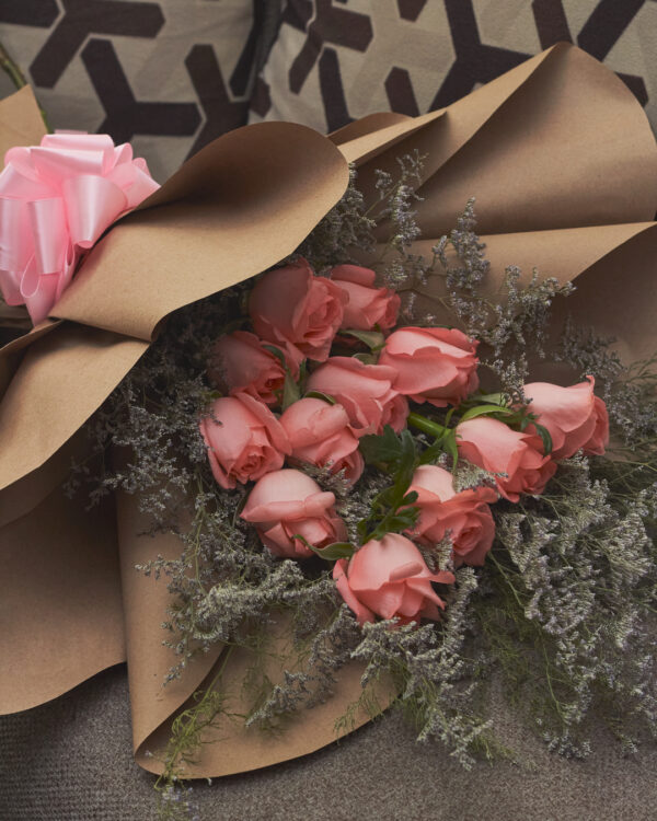 Detalle cercano de rosas rosadas y caspia en ramo con estructura en niveles, envuelto en papel kraft, mostrando textura y volumen floral.