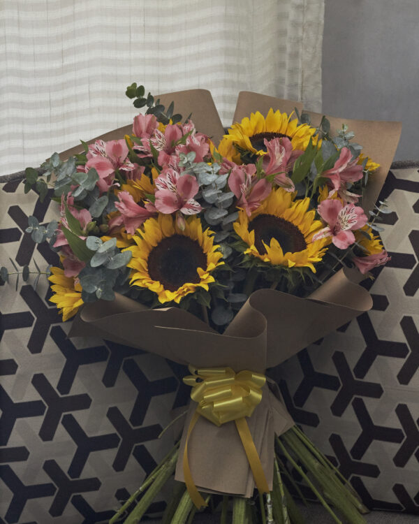 Ramo con girasoles, astromelias y mini dólar, composición floral equilibrada vista de frente.