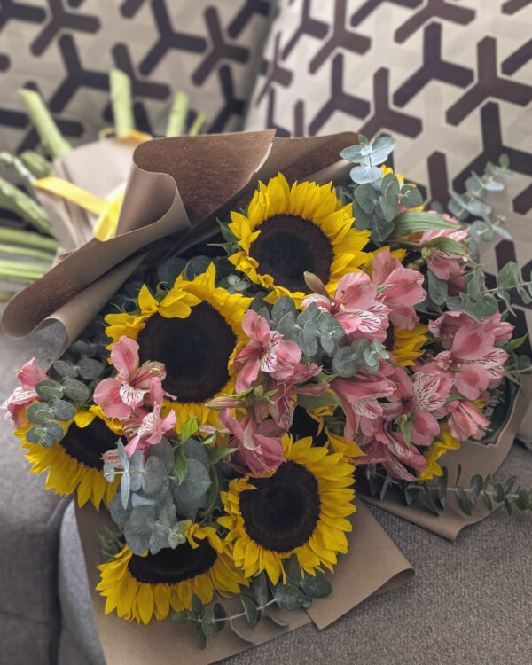 Detalle cercano de flores en ramo con girasoles, astromelias y mini dólar, mostrando texturas y contraste natural.