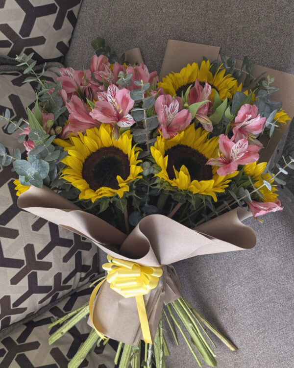 Vista superior de ramo mixto con girasoles, astromelias y mini dólar, arreglo floral redondo y armonioso.