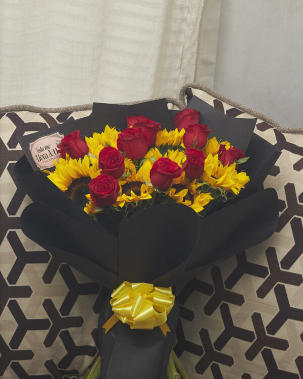 Ramo de girasoles con rosas rojas envuelto en papel negro, composición floral contrastante vista de frente.