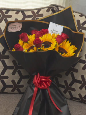 Ramo de girasoles con rosas rojas envuelto en papel coreano negro, arreglo floral contrastante visto de frente.
