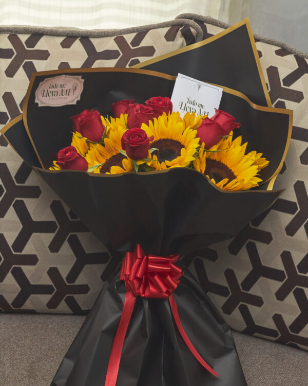 ramo_de_girasoles_y_rosas_rojas_con_papel_coreano_1 Ramo de girasoles con rosas rojas envuelto en papel coreano negro, arreglo floral contrastante visto de frente.