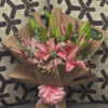 ramo_de_lirios_rosas_astromelias_minidolar_1 Ramo de lirios rosas con astromelias y mini dólar envuelto en papel kraft, arreglo floral elegante visto de frente.
