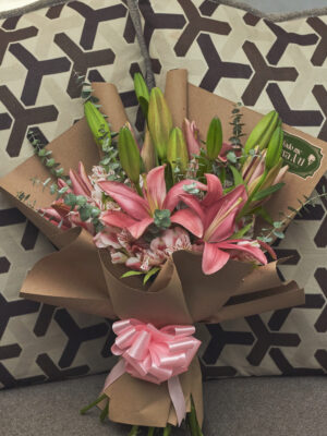 Ramo de lirios rosas con astromelias y mini dólar envuelto en papel kraft, arreglo floral elegante visto de frente.