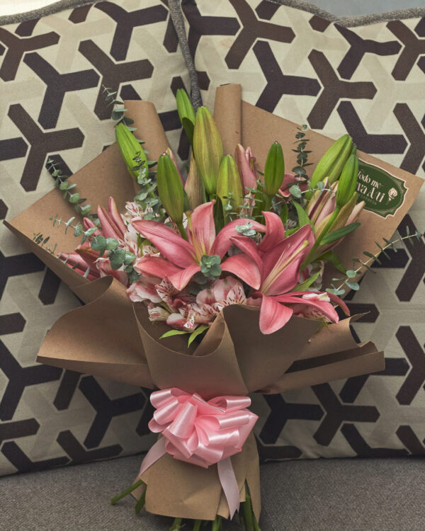 ramo_de_lirios_rosas_astromelias_minidolar_1 Ramo de lirios rosas con astromelias y mini dólar envuelto en papel kraft, arreglo floral elegante visto de frente.