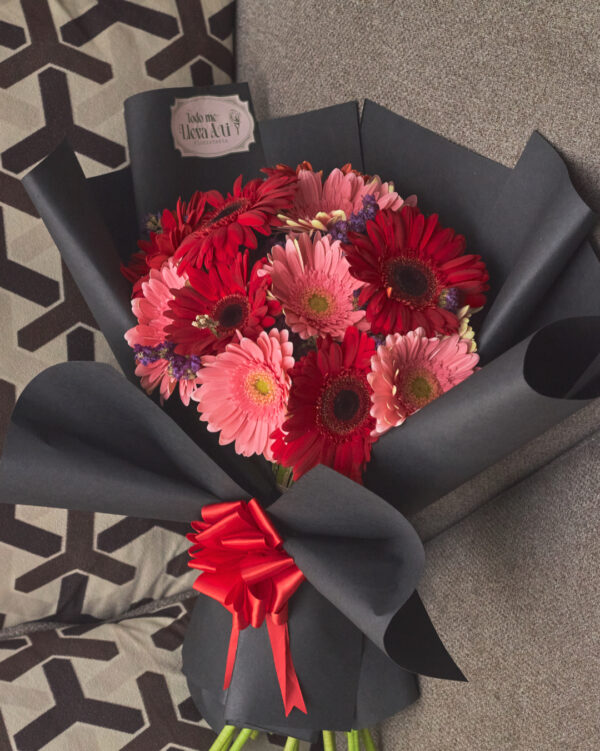 ramo_de_gerberas_bicolor_con_statice_2 Vista superior de ramo redondo con gerberas en dos colores y flor statice, envuelto en papel negro.