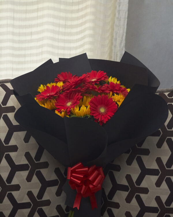 ramo_de_girasoles_con_gerberas_1 Ramo de girasoles con gerberas rojas envuelto en papel negro, composición floral de alto contraste vista de frente.