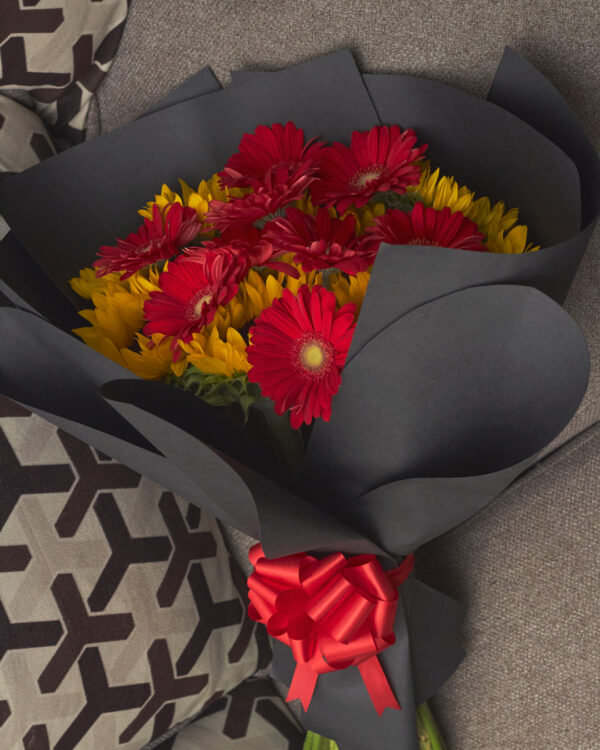 ramo_de_girasoles_con_gerberas_3 Vista superior de ramo con girasoles y gerberas rojas envuelto en papel negro, arreglo floral redondo y contrastante