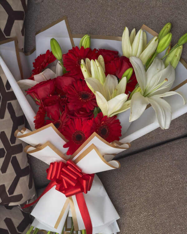 Vista superior de ramo con gerberas, rosas rojas y lirios blancos, envuelto en papel coreano blanco y con estructura coreana.